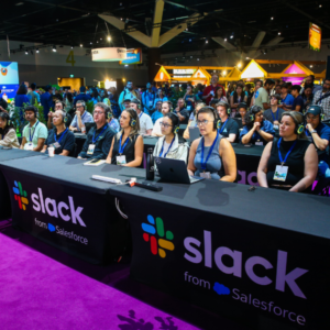 An image of a tech conference featuring a large tablecloth printed with slack and salesforce branding